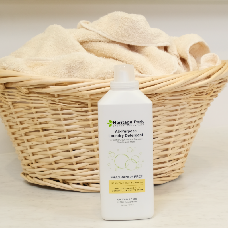 32 oz bottle of Heritage Park  Fragrance Free All-Purpose Laundry Detergent next to a basket of towels