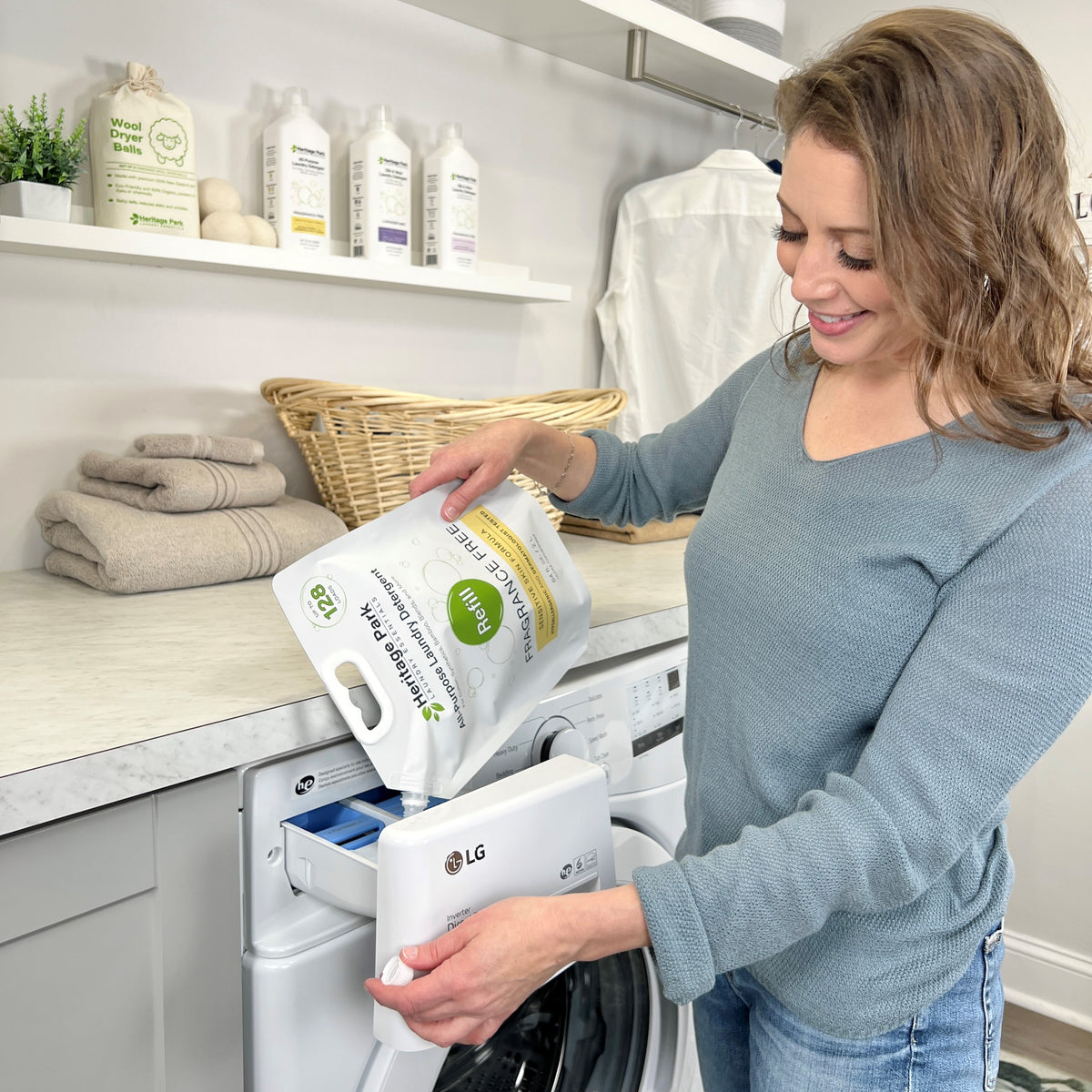 Women pouring Heritage Park All Purpose Fragrance Free Laundry Detergent into a washing machine